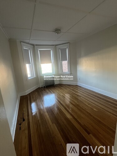 A room with wooden floors and three windows.