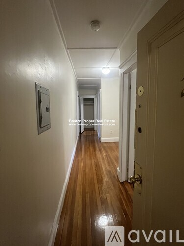 A long hallway with wooden floors and white walls.