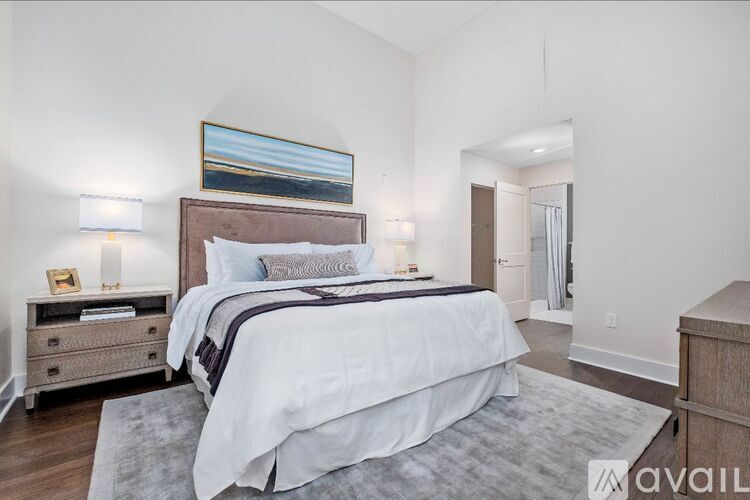 A bedroom with a large bed and a painting on the wall.