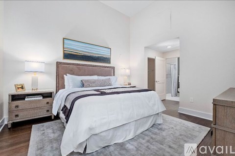 A bedroom with a large bed and a painting on the wall.