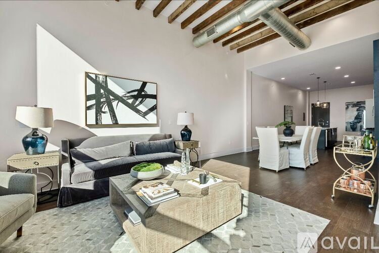 A modern living room with a glass coffee table and a large abstract painting on the wall.