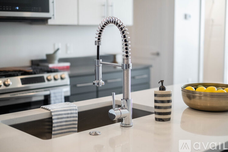 A kitchen sink with a striped soap holder and a bowl of lemons.