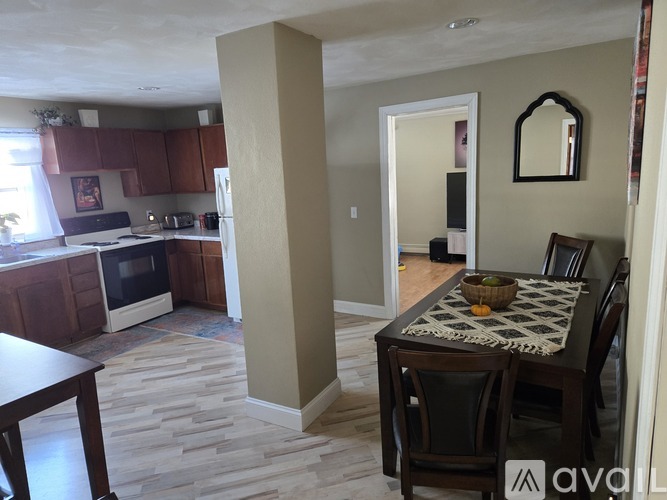 A kitchen with a table and chairs in the foreground and a hallway in the background.