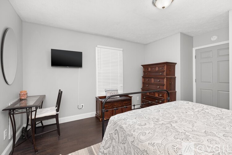 A bedroom with a bed, dresser, and chair.