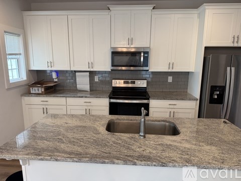 A kitchen with granite countertops and white cabinets.
