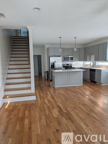 A spacious kitchen and living room with wooden flooring and a staircase.