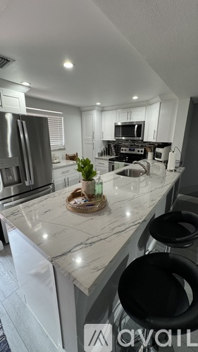 A kitchen with a marble countertop and black bar stools.