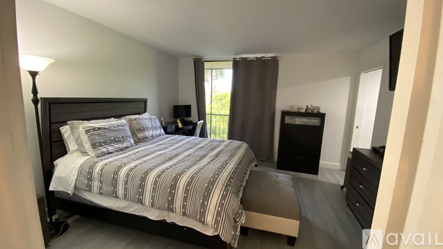 A bedroom with a large bed and a window with curtains.