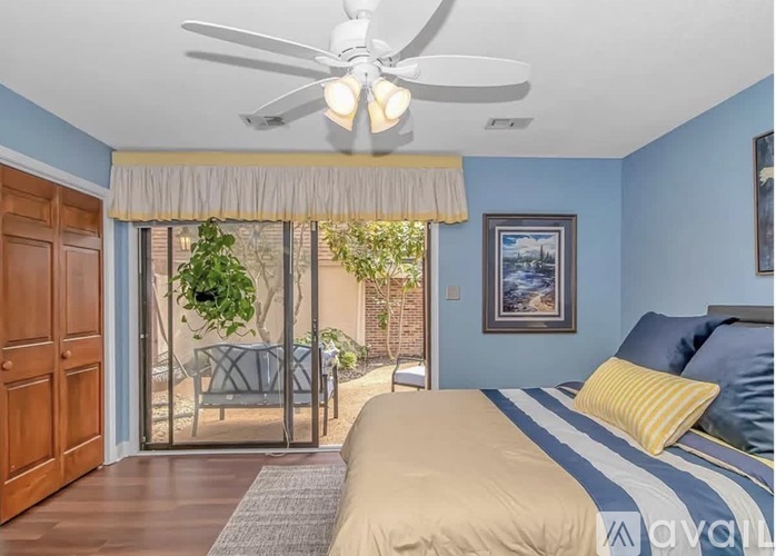 A bedroom with a bed, a ceiling fan, and a sliding glass door leading to a patio.