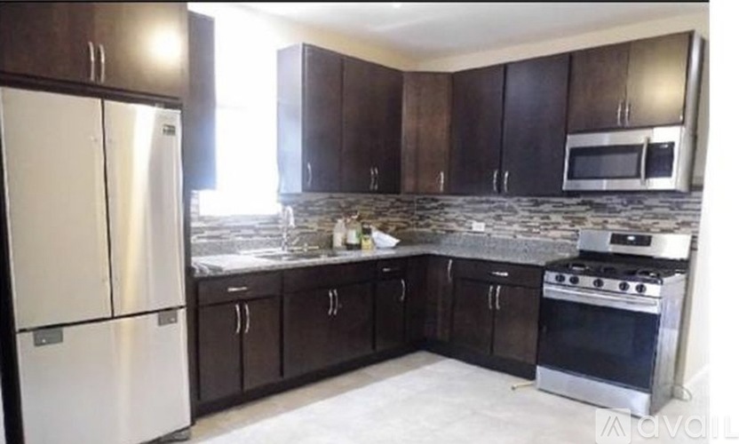 A kitchen with a white refrigerator, black cabinets, and a granite countertop.