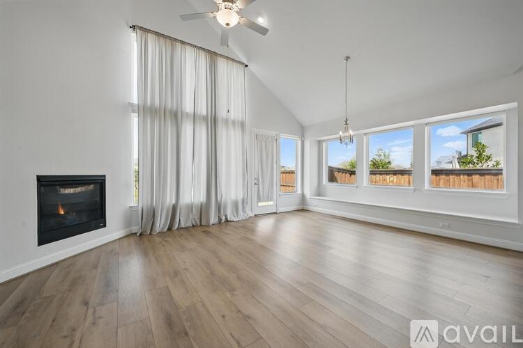A spacious room with a fireplace and a view of the outdoors through the windows.
