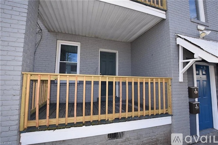 A balcony with a wooden railing and a blue door.