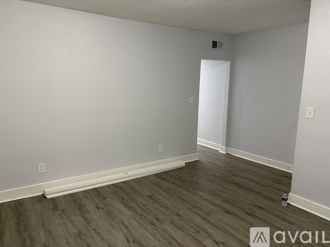 A room with wooden flooring and white walls.