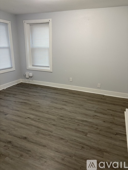 A room with wooden flooring and a window with blinds.