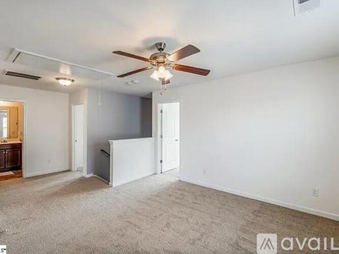 A room with a ceiling fan and carpeted floor.