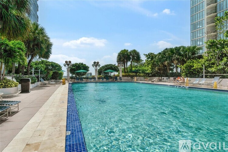 A large outdoor swimming pool surrounded by palm trees and lounge chairs.