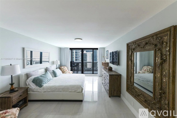 A bedroom with a large bed, a wooden nightstand, and a large mirror on the wall.