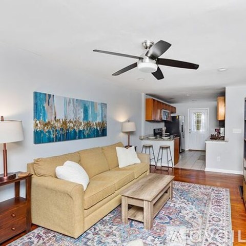 A living room with a tan couch and a ceiling fan.