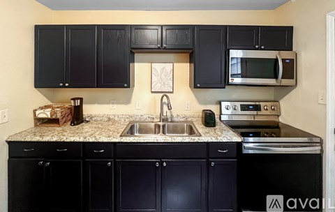 A kitchen with black cabinets and granite countertops.