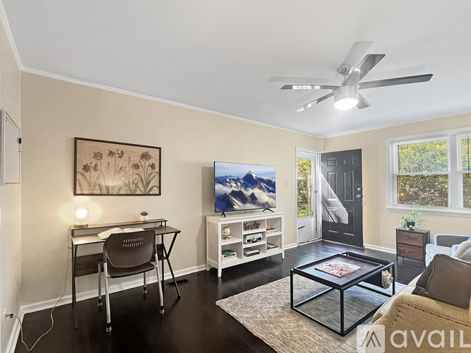 A living room with a brown chair, a black coffee table, and a painting on the wall.