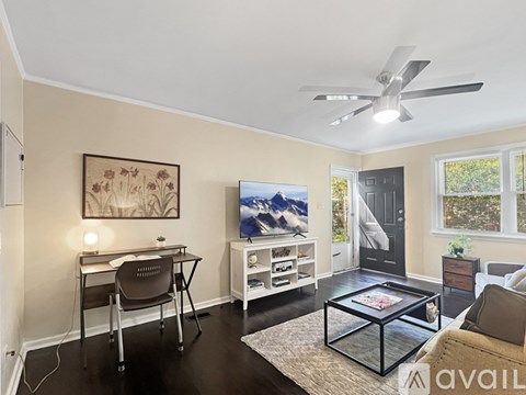 A living room with a brown chair, a black coffee table, and a painting on the wall.