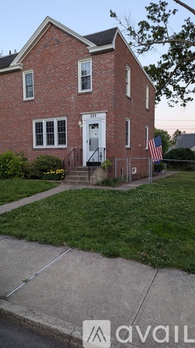 A red brick house with a white door and a small American flag on the front porch.