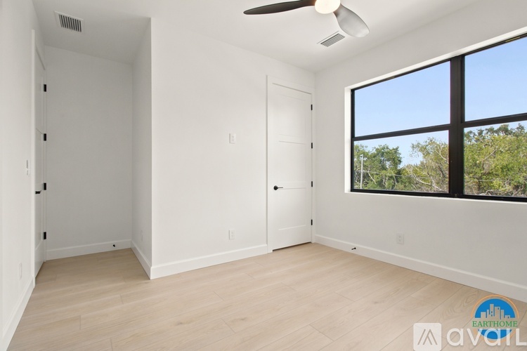 A spacious room with a ceiling fan and a large window overlooking trees.