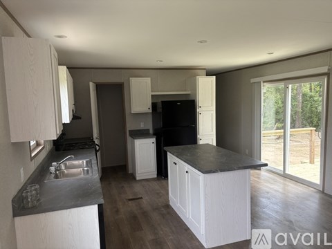 A kitchen with white cabinets and a black countertop.