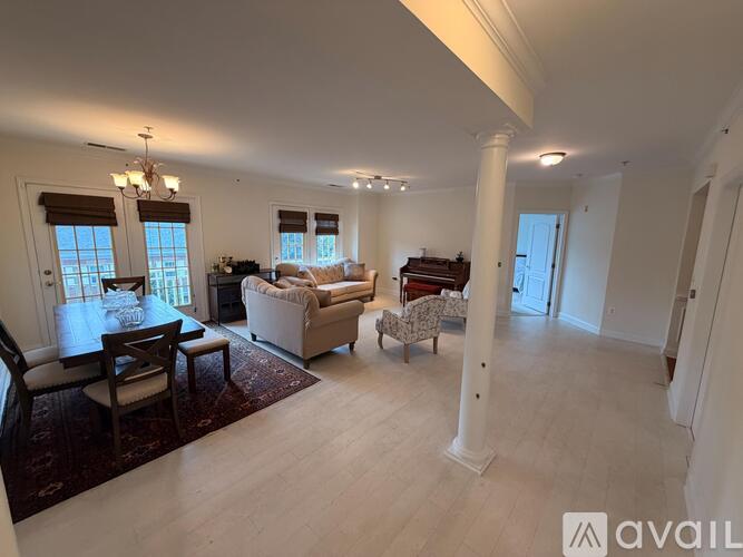 A spacious living room with a dining table and chairs, a sofa, and a piano.