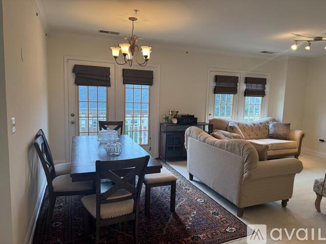 A dining room with a table set for two and a couch.