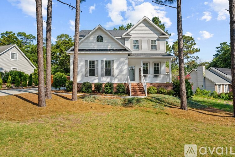 A house with a front yard and a tree in front of it.