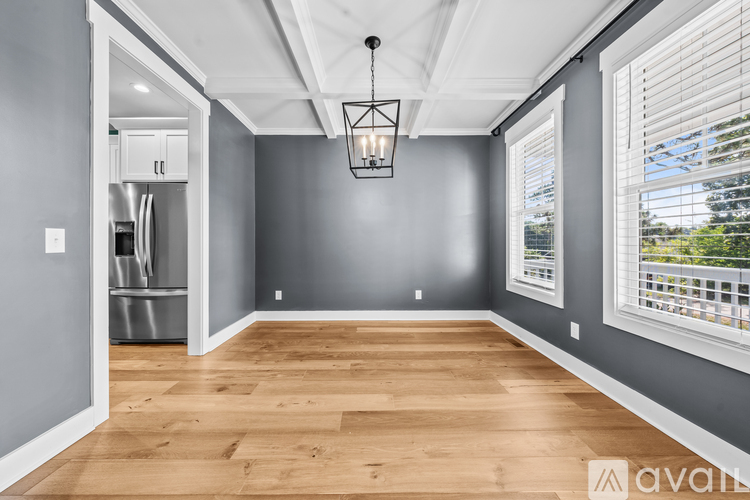 A spacious room with wooden flooring and a hanging light fixture.