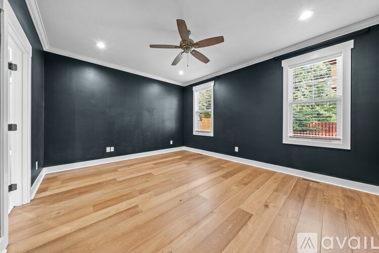 A room with a ceiling fan and a window with a view of trees.