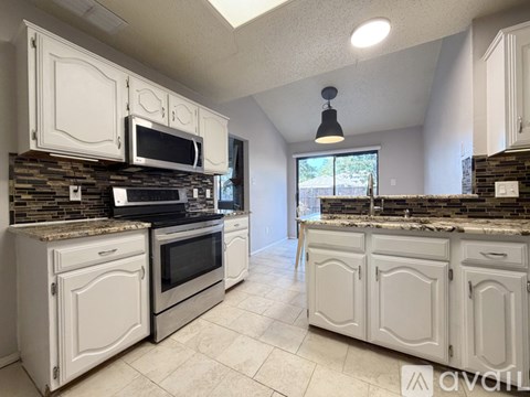 A kitchen with white cabinets and a stone backsplash.