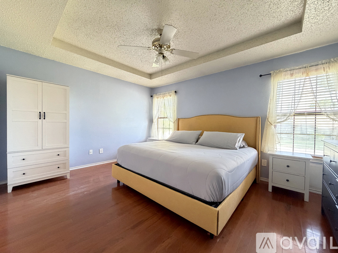 A bedroom with a bed, dresser, and ceiling fan.