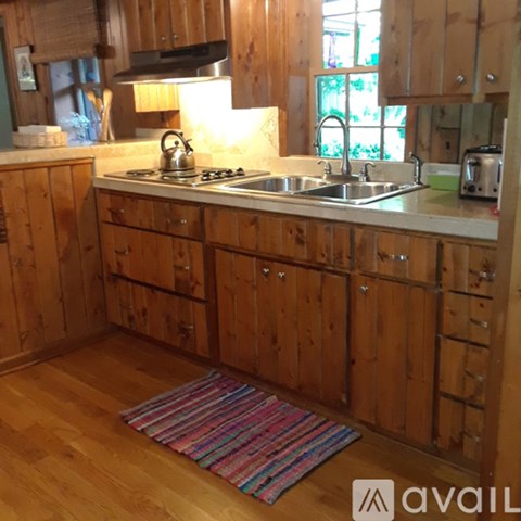 A kitchen with wooden cabinets and a striped rug on the floor.
