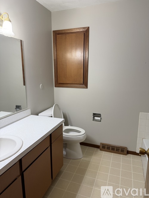 A bathroom with a toilet, sink, and mirror.