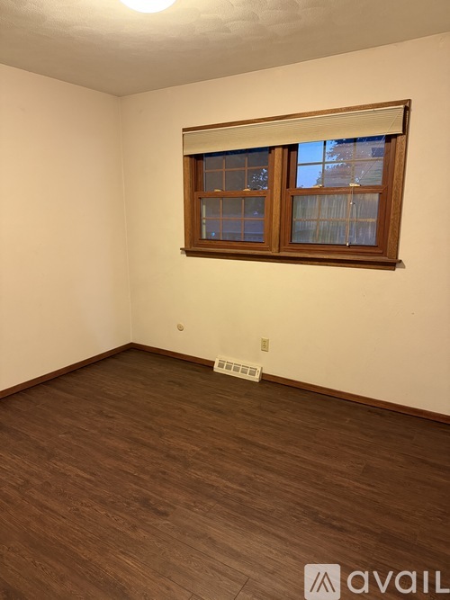 A room with a window and wooden flooring.