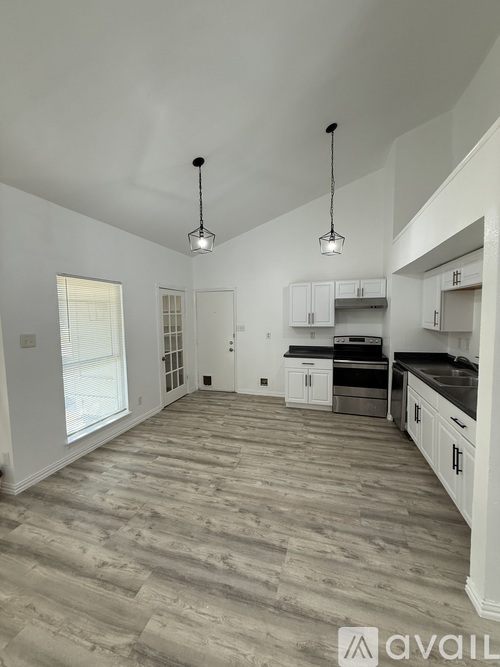 A kitchen with a large island and pendant lights.