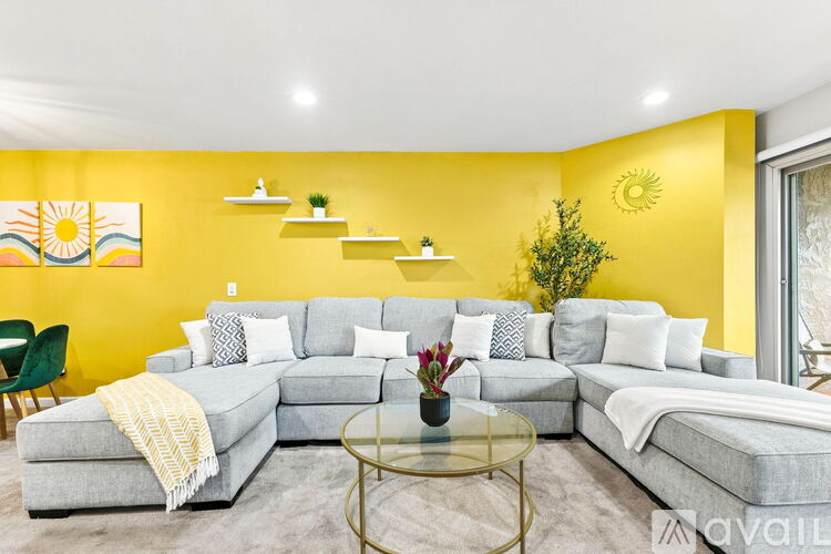 A living room with a grey sectional sofa and a yellow wall.