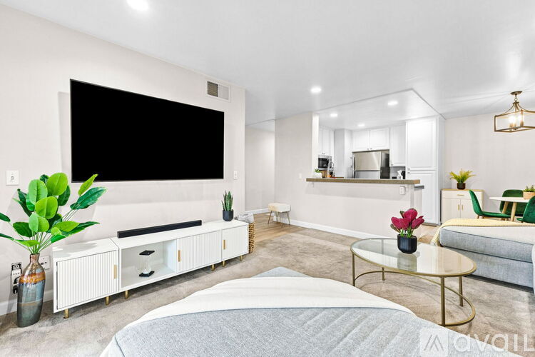 A modern bedroom with a large bed and a flat-screen TV mounted on the wall.