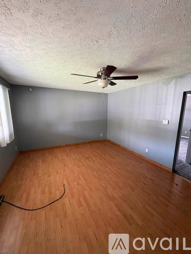 A room with a ceiling fan and wooden flooring.