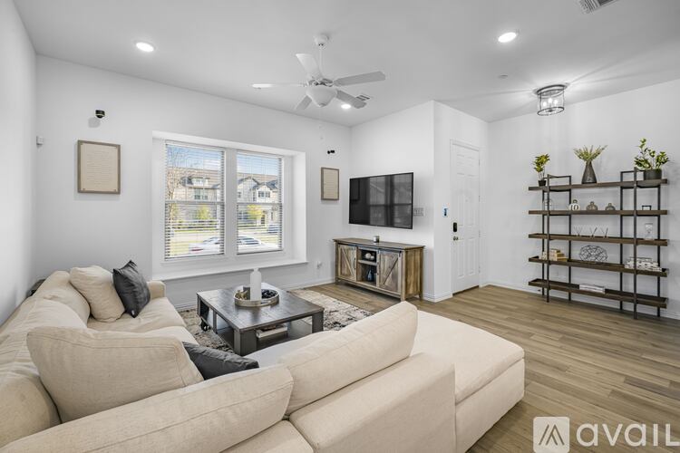 A living room with a beige couch, a coffee table, and a flat-screen TV.
