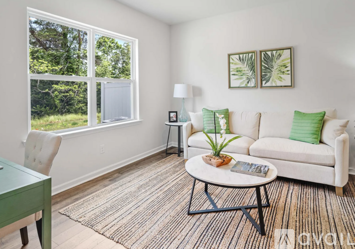 A living room with a white couch, a green desk, and a rug.