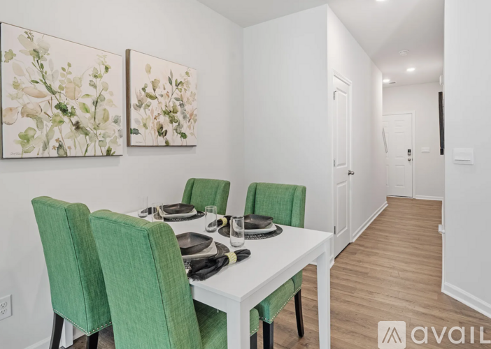 A dining room with a white table and green chairs.