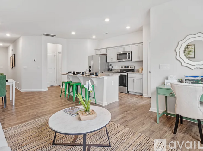 A modern kitchen with white cabinets and a dining table with green chairs.