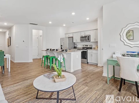A modern kitchen with white cabinets and a dining table with green chairs.