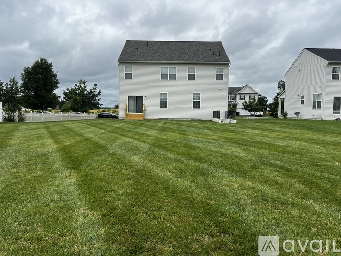 A white house with a grey roof and a green lawn in front.