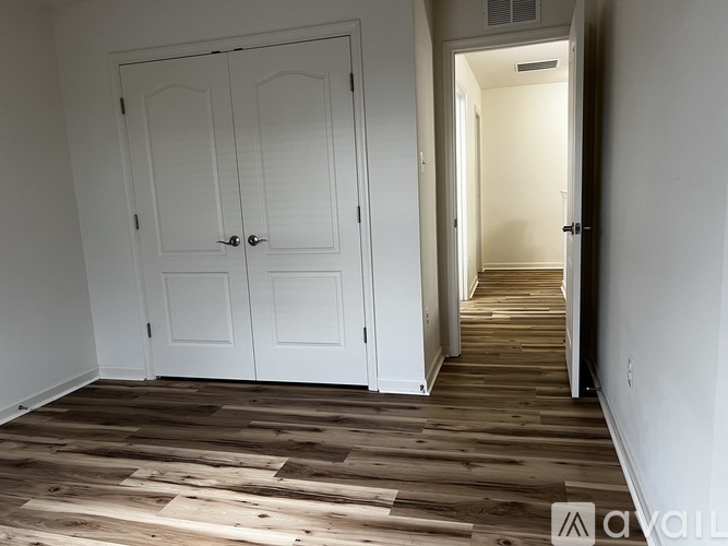 A room with a white door and wooden flooring.