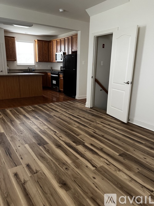 A kitchen with wooden floors and a black refrigerator.